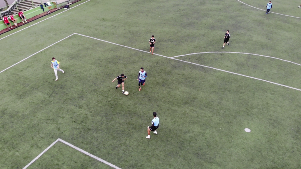 Jugadores de fútbol de la escuela Tepichines Soccer en un campo durante un partido, vistos desde una perspectiva aérea.